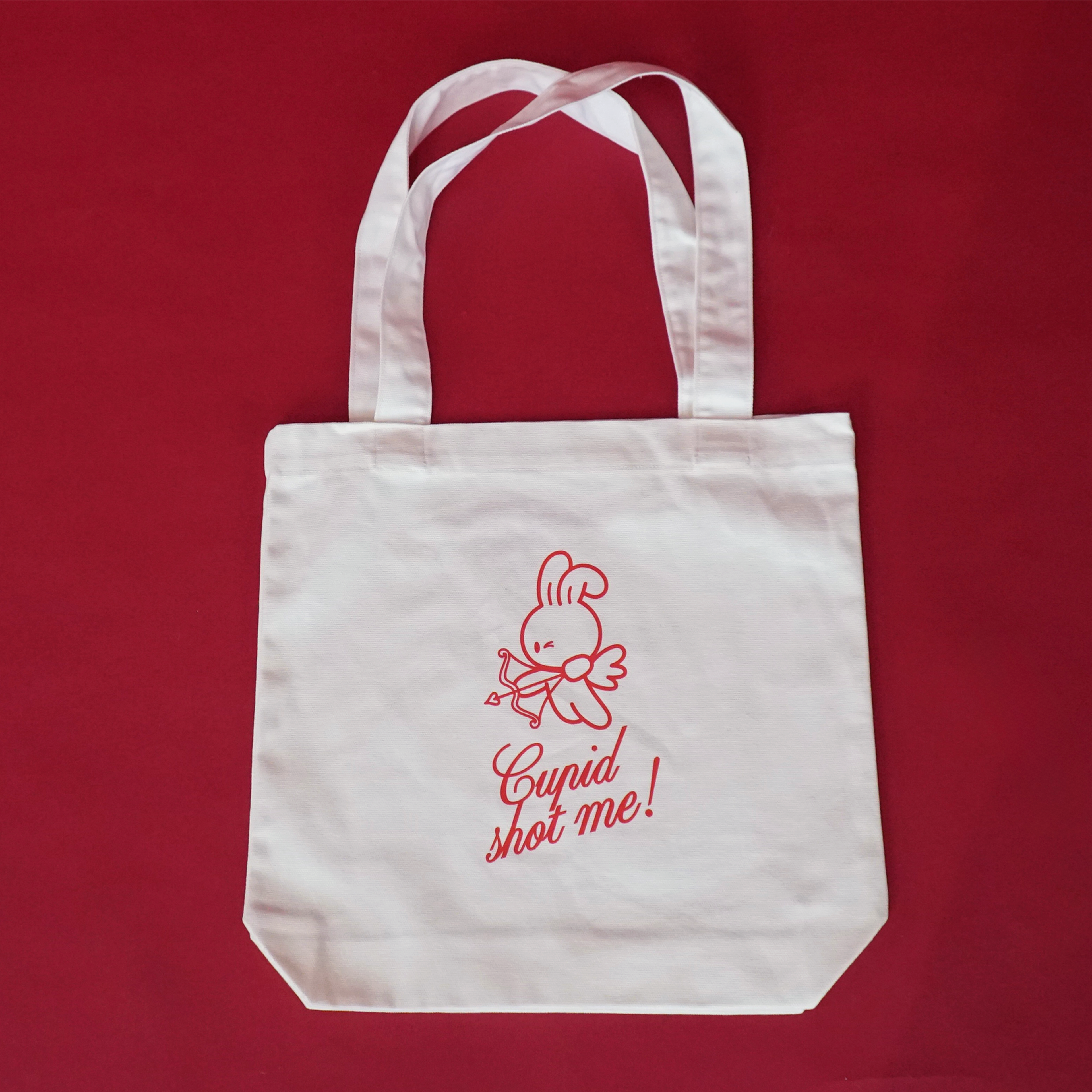 White tote bag with red text and bunny graphics on a red background